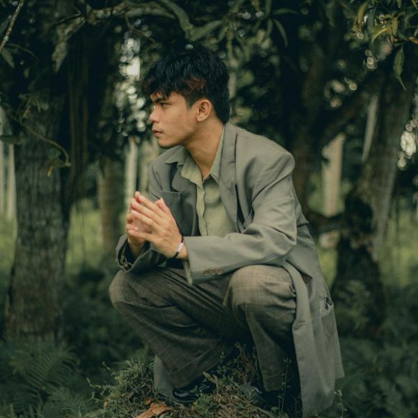 Focused man meditating in a calm, dimly lit environment with a green glow.