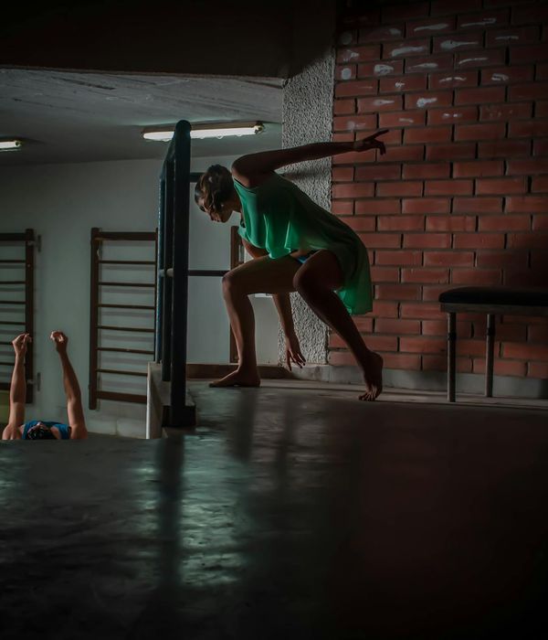Man performing a controlled strength exercise in a dark studio with green light.